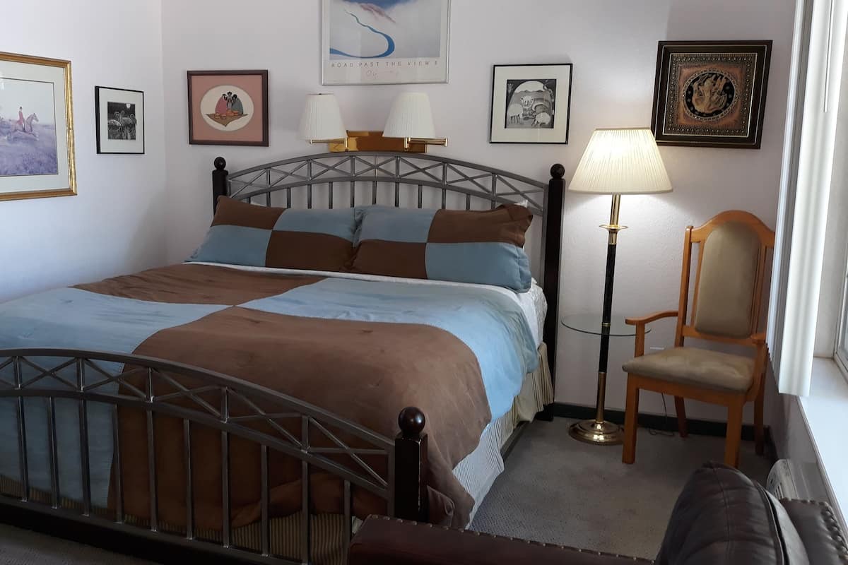A neatly arranged bedroom with a bed, a chair, and a lamp.