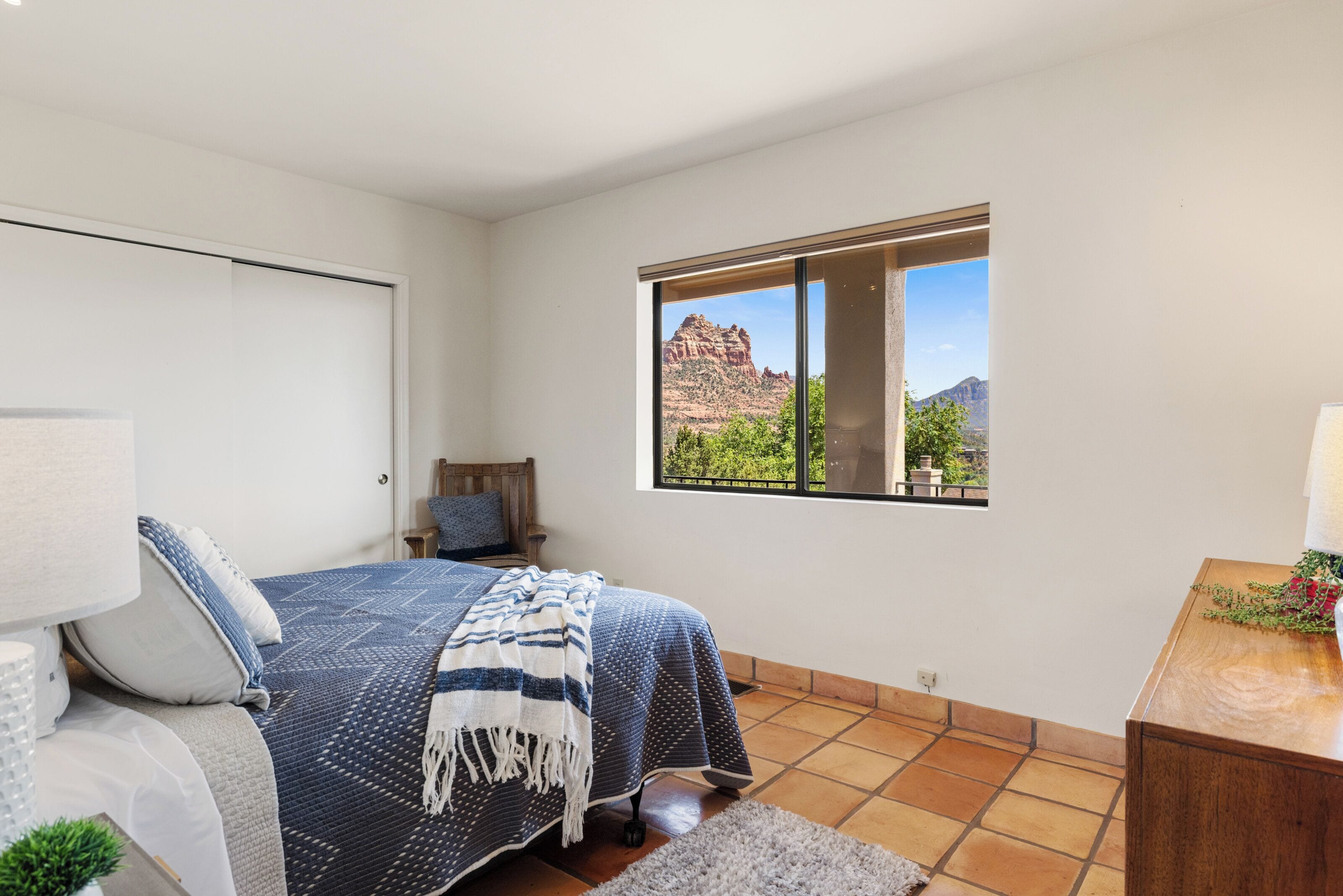 Una camera da letto con un letto, una finestra vista montagna e un comodino in legno.