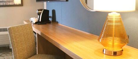 Une chambre d’hôtel avec un bureau en bois, une chaise, un téléviseur fixé au mur et un miroir.