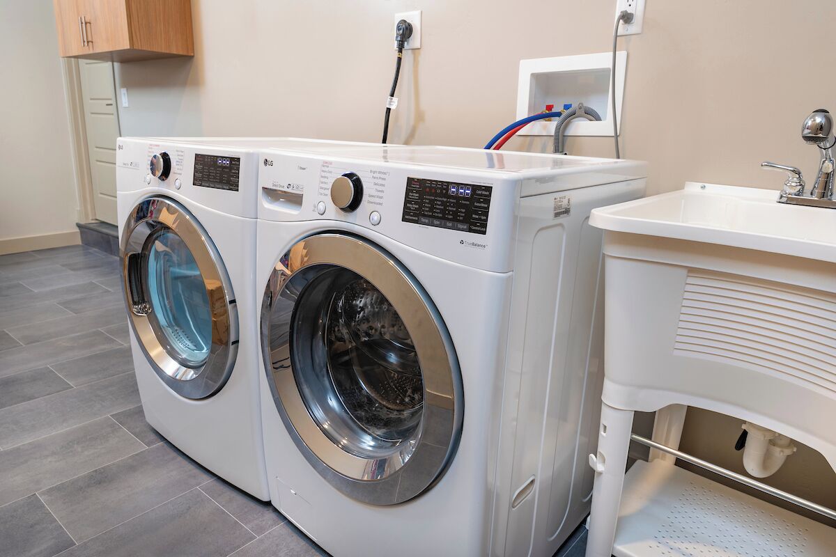 A laundry area with two front-loading washing machines and a sink.