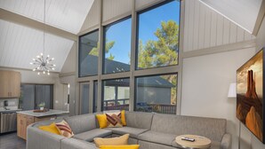 A modern interior with a sectional sofa, a small round table, and a large window offering a view of trees and a mountain. - Matterhorn Inn (Sedona)