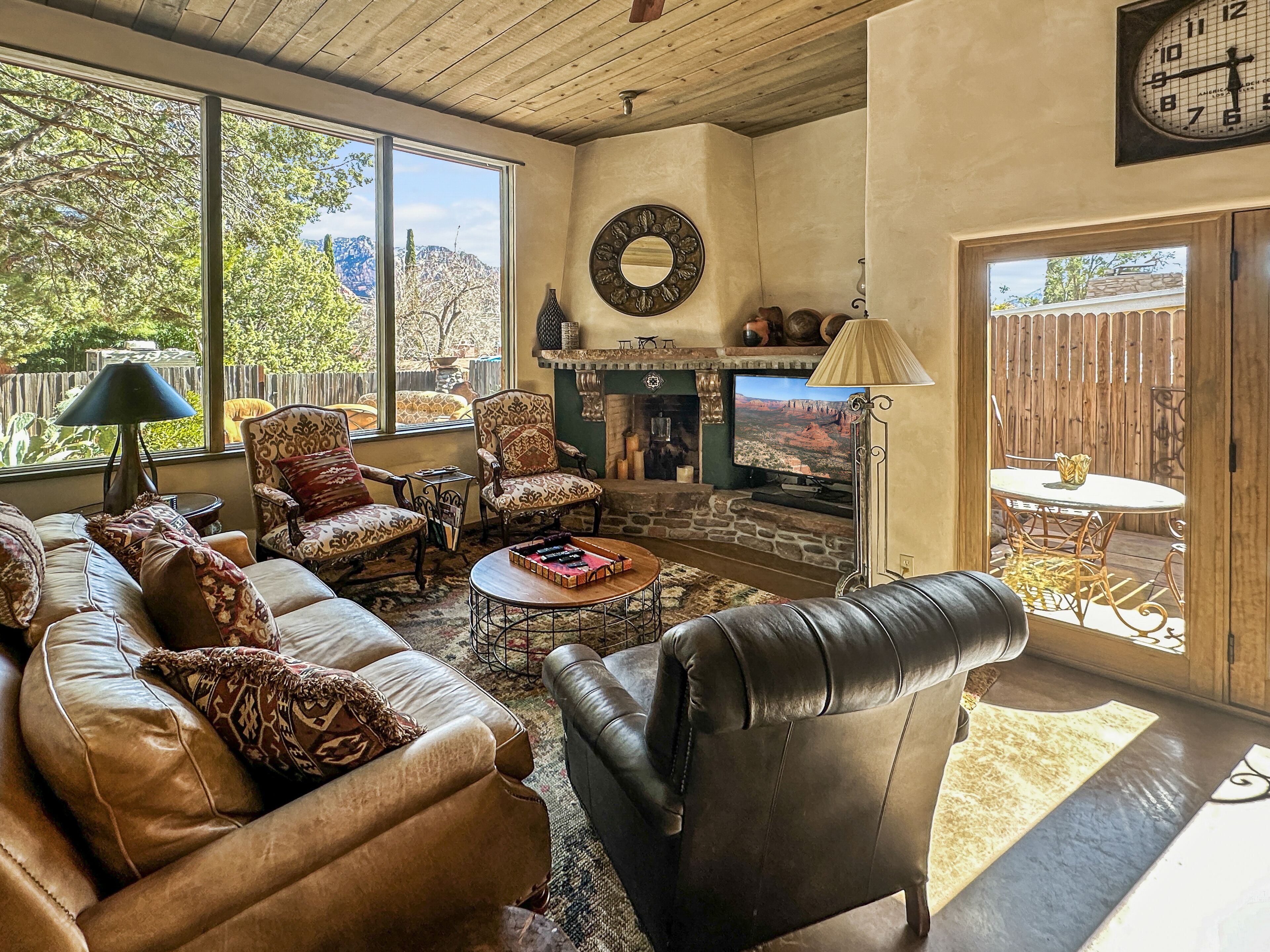 A cozy living room with a fireplace, leather sofas, and a large window overlooking a scenic view.