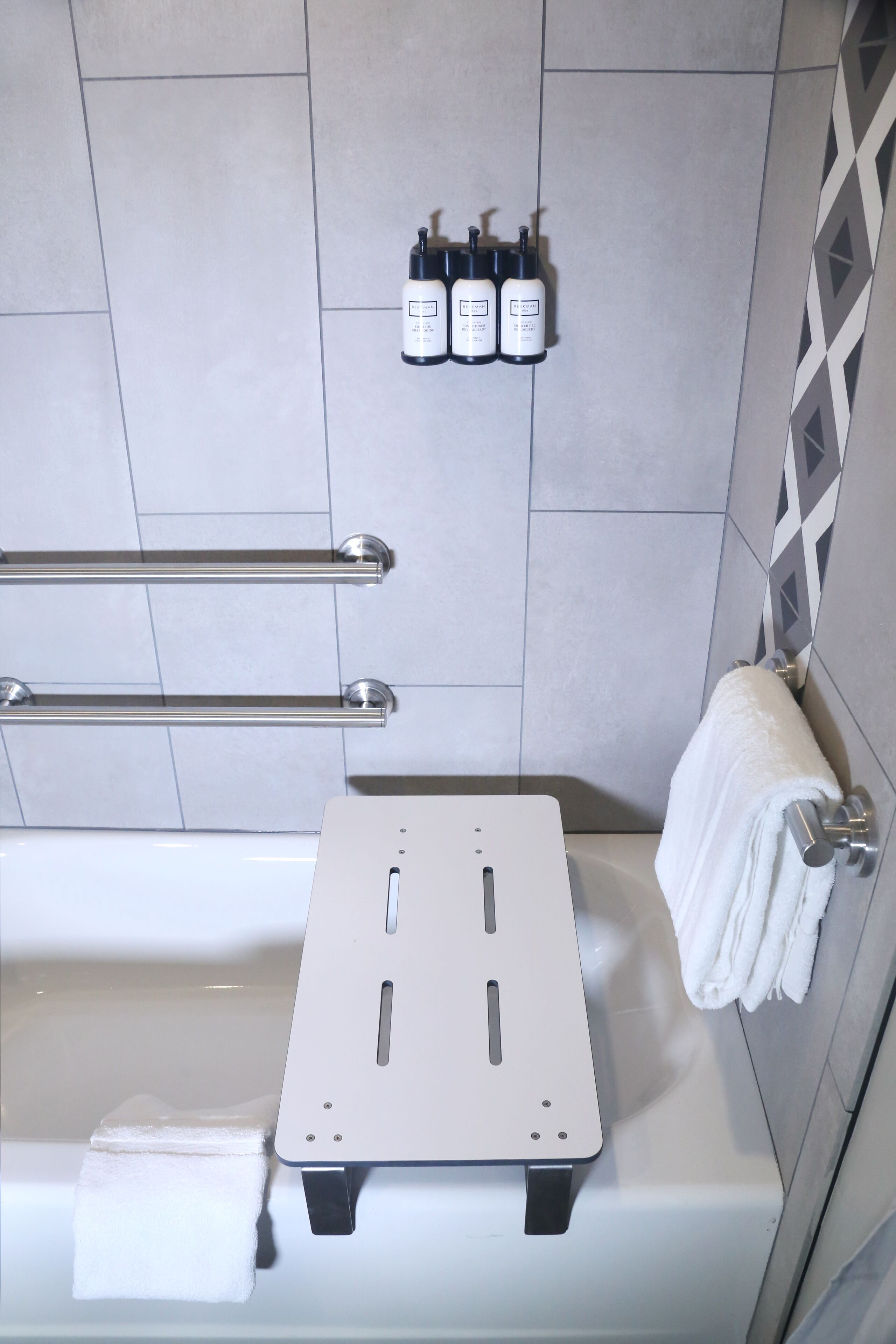 A bathroom with a white bathtub, a towel rack, and a set of toiletries on the wall.