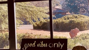A window with a view of a mountainous landscape and a sign that reads "good vibes only". - Matterhorn Inn (Sedona)