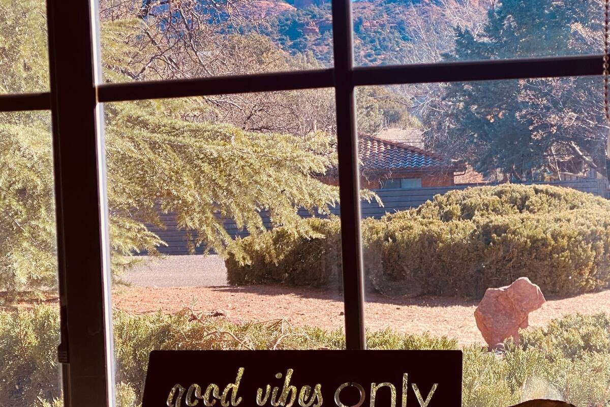 A window with a view of a mountainous landscape and a sign that reads "good vibes only".