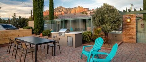 An outdoor patio with a grill, seating, and a view of mountains.