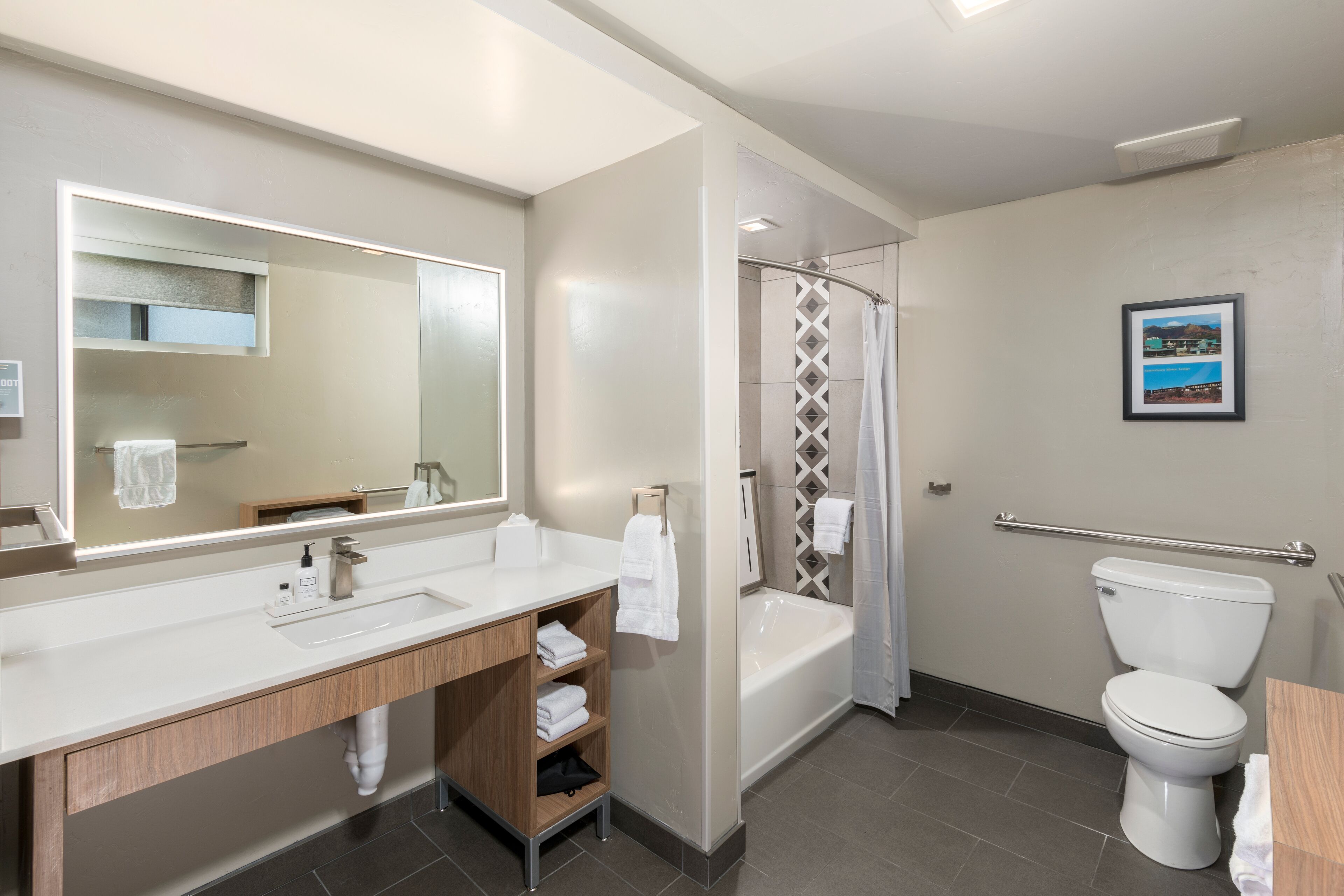 Un baño moderno con un espejo grande, un lavabo, ducha e inodoro.