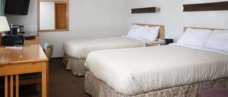 A hotel room with two beds, a desk with a lamp, a television, and a mirror.