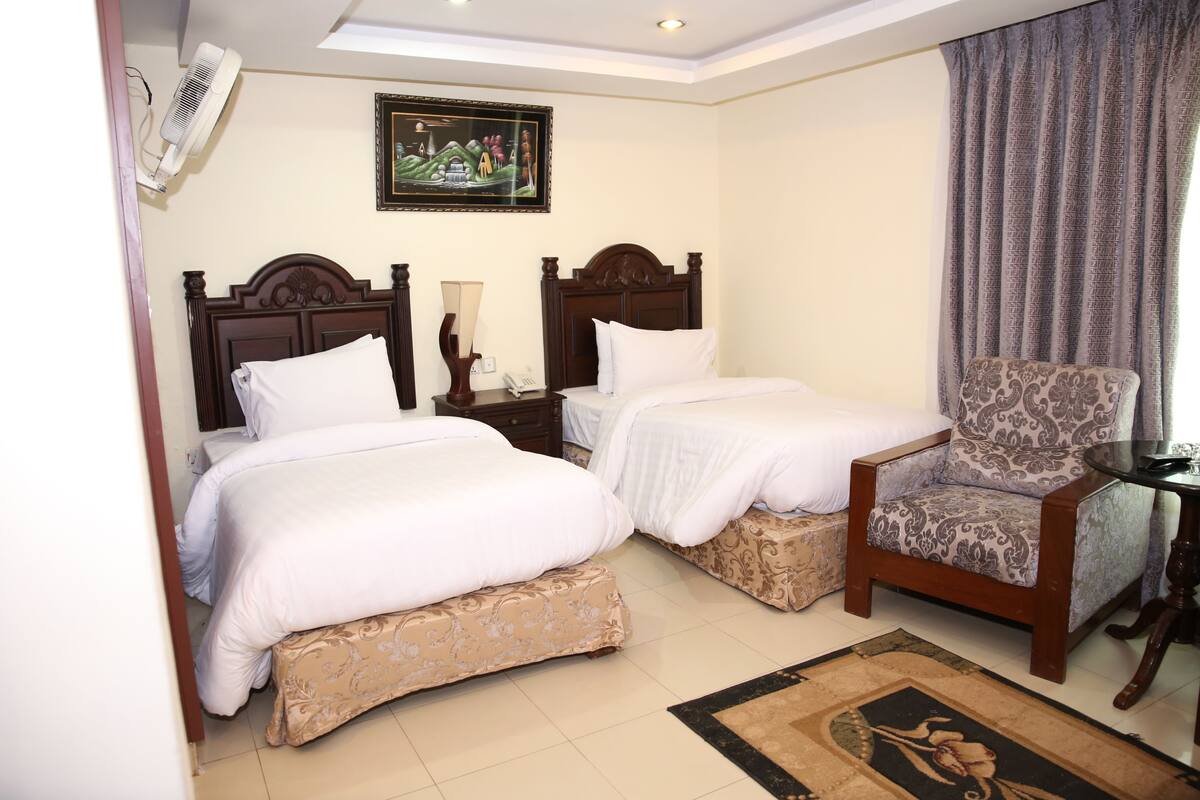 Une chambre d’hôtel avec deux lits, une chaise, une table et un tableau au mur.