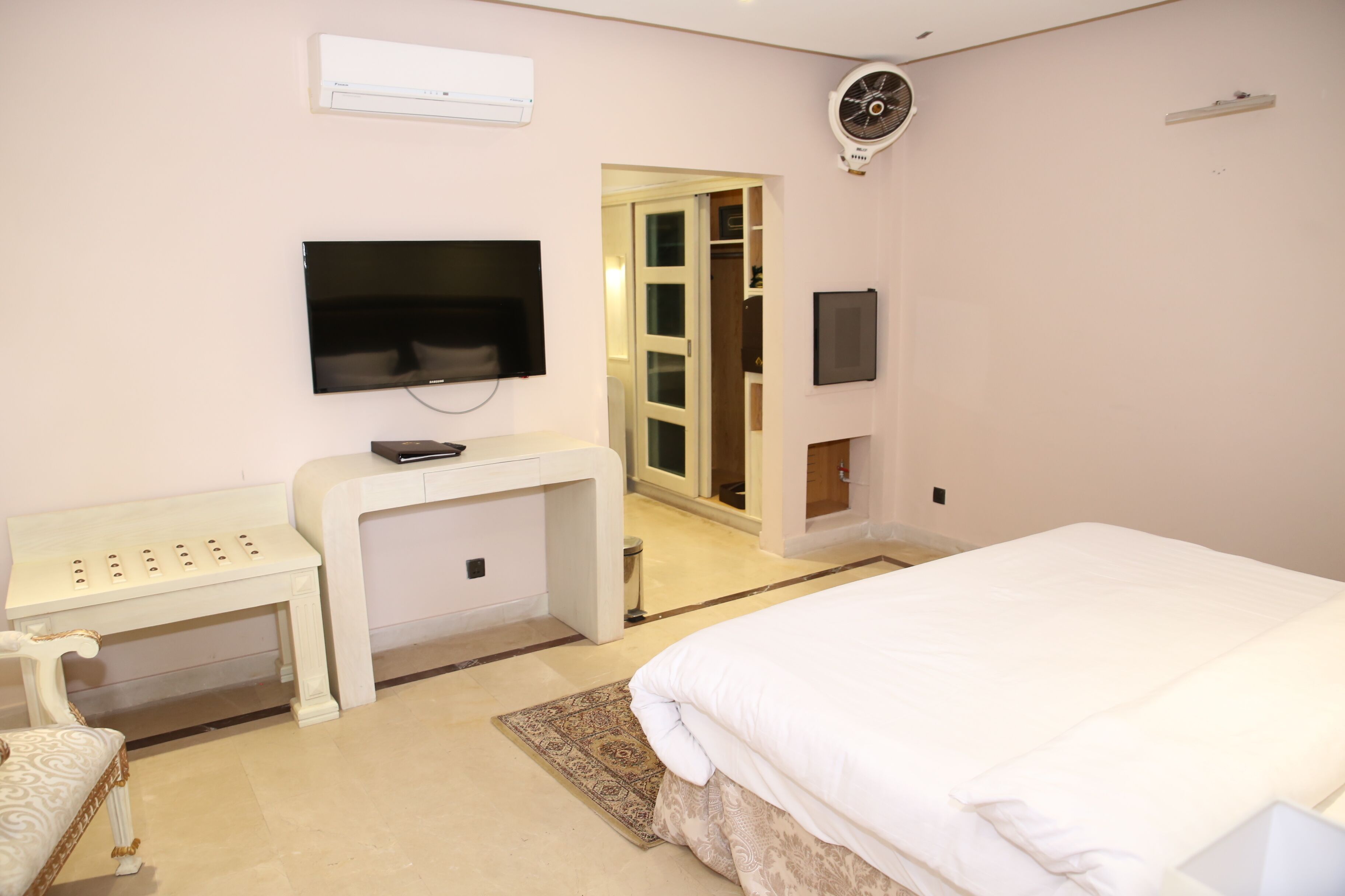 Un dormitorio con cama, televisor, escritorio y armario.