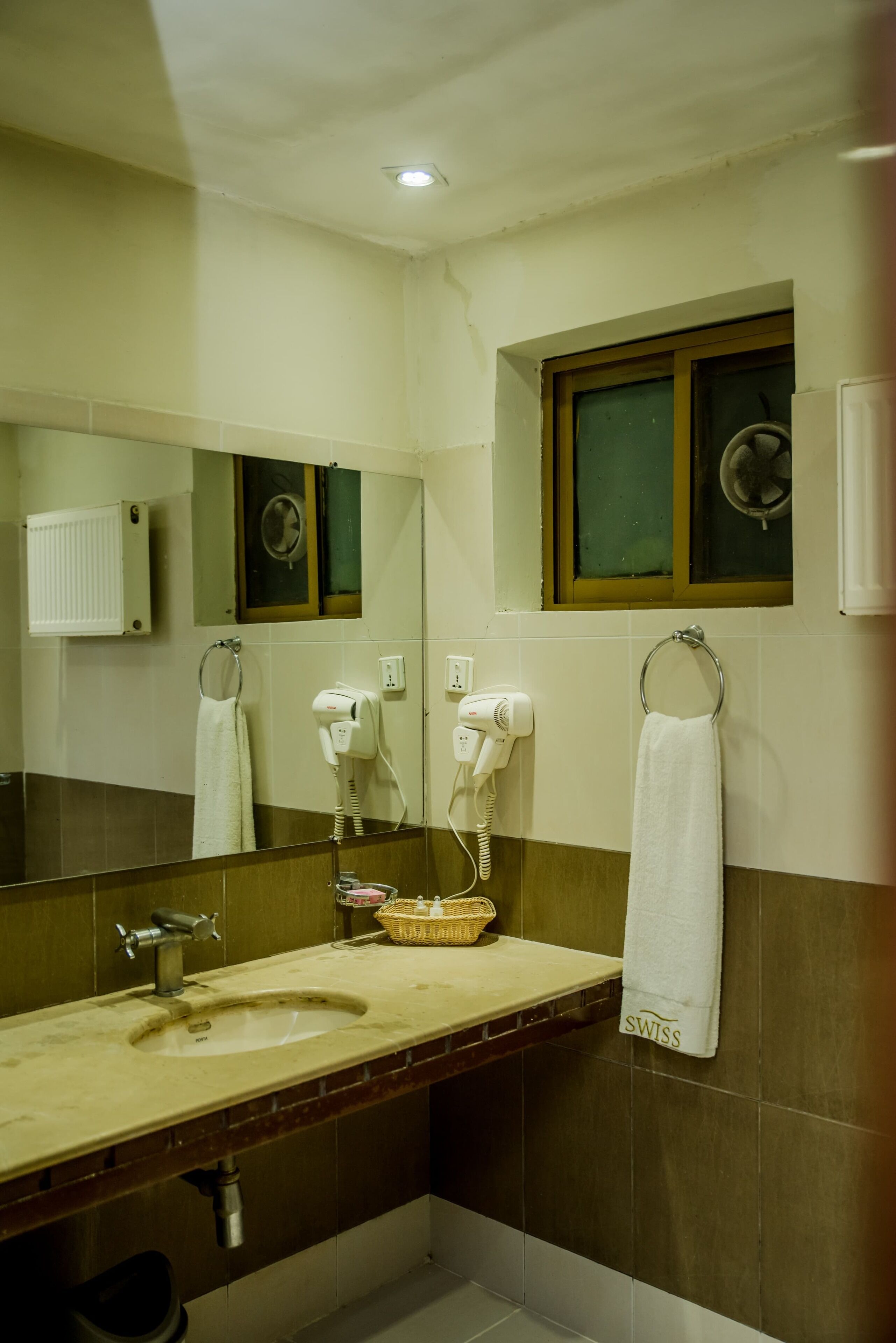 Baño con lavamanos, espejo, toallero y secador de pelo.