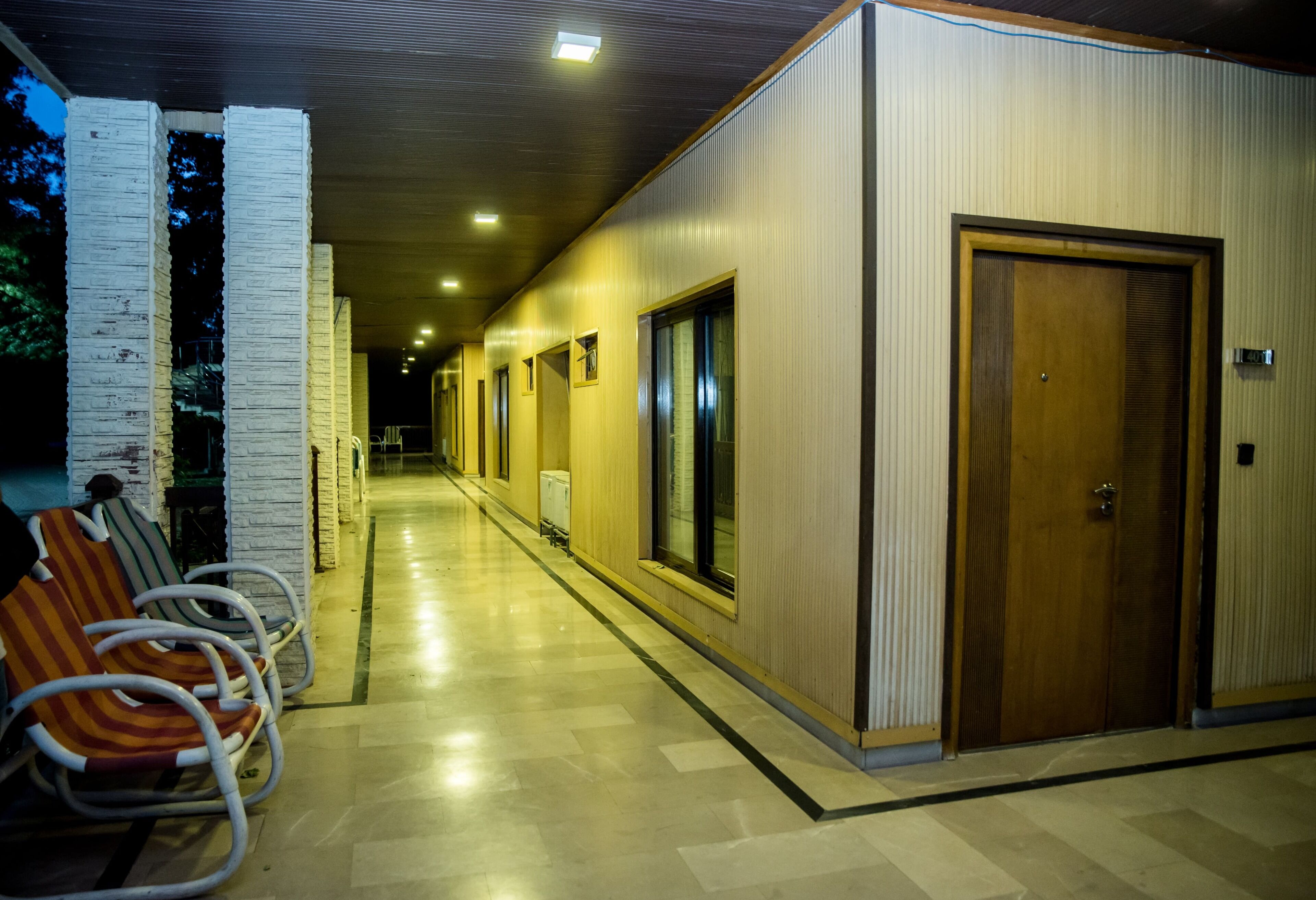 A hallway with a wooden door, a bench, and a wall with a window.