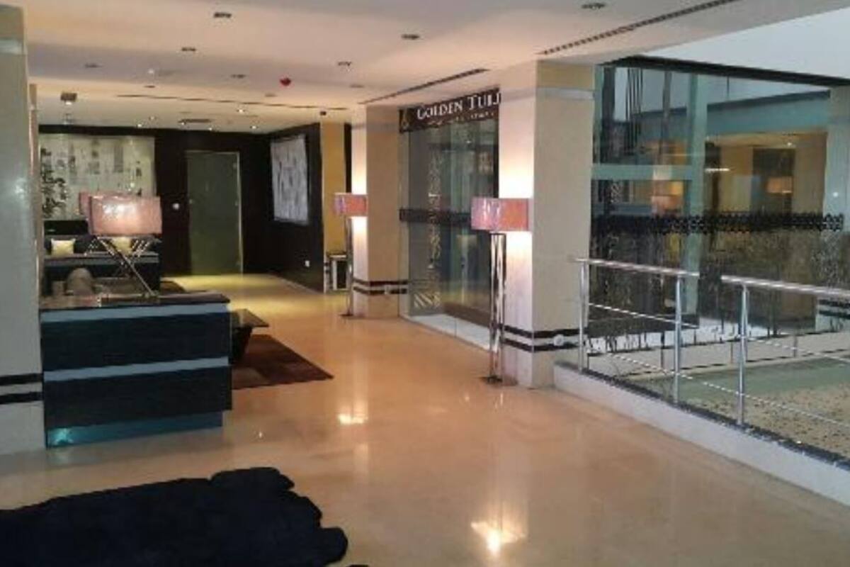 Un hall d’hôtel moderne avec un comptoir d’accueil, une rambarde en verre et une vue sur l’espace extérieur.