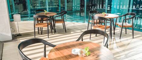 A modern indoor space with glass walls, wooden tables, and chairs.
