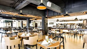 Un restaurant modern amb taules i cadires rodones, il·luminació penjant i una zona de bar.