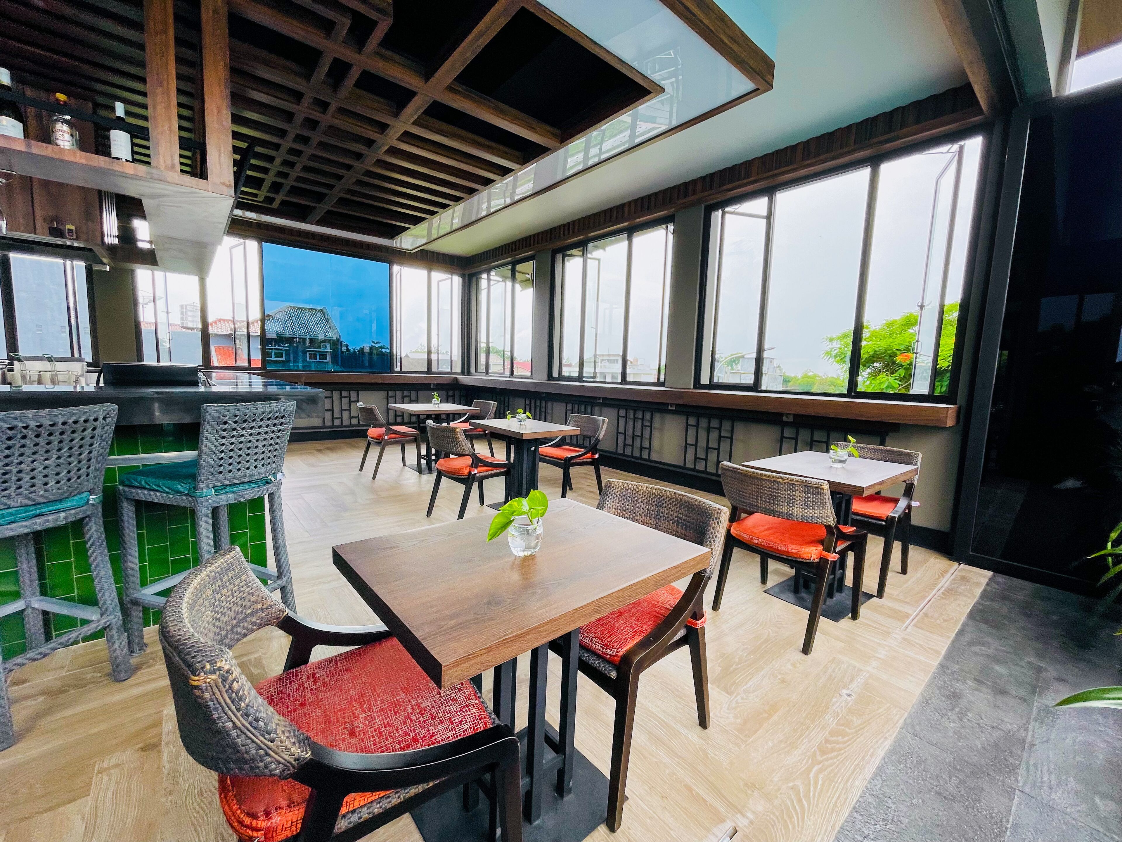 A restaurant with wooden tables and chairs, large windows, and a view of the city.