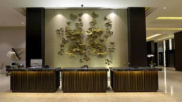 Un área de recepción con tres mostradores, un panel decorativo en la pared y una planta en maceta.