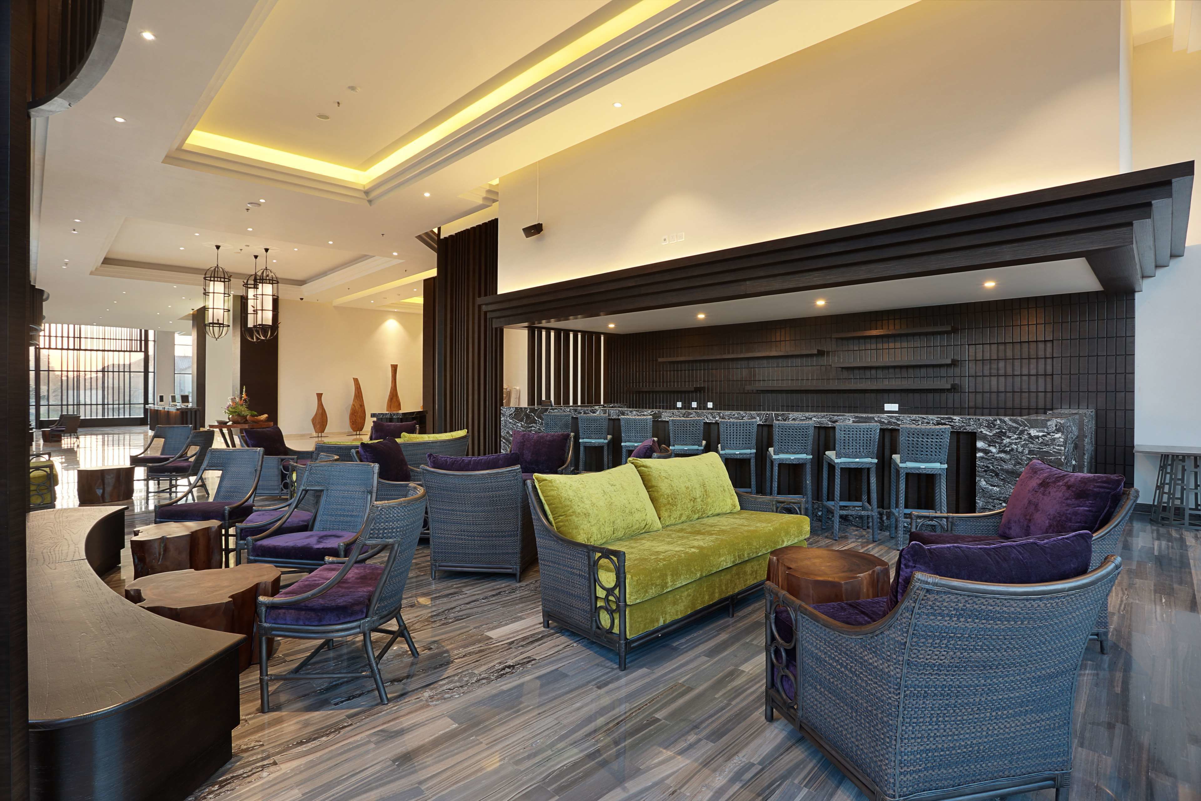 A modern lounge area with wicker furniture, a central sofa, and a bar counter.