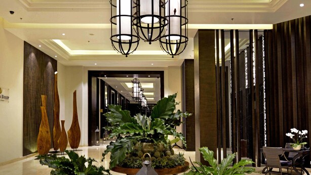 Un hall d'hôtel doté d'un lustre moderne, de plantes en pot et d'un espace salon.