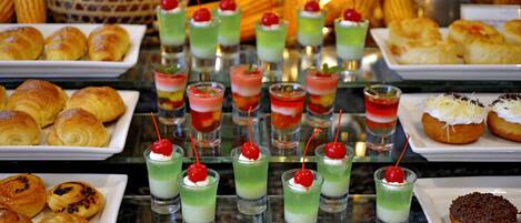 A buffet with various food items including pastries, desserts, and drinks.