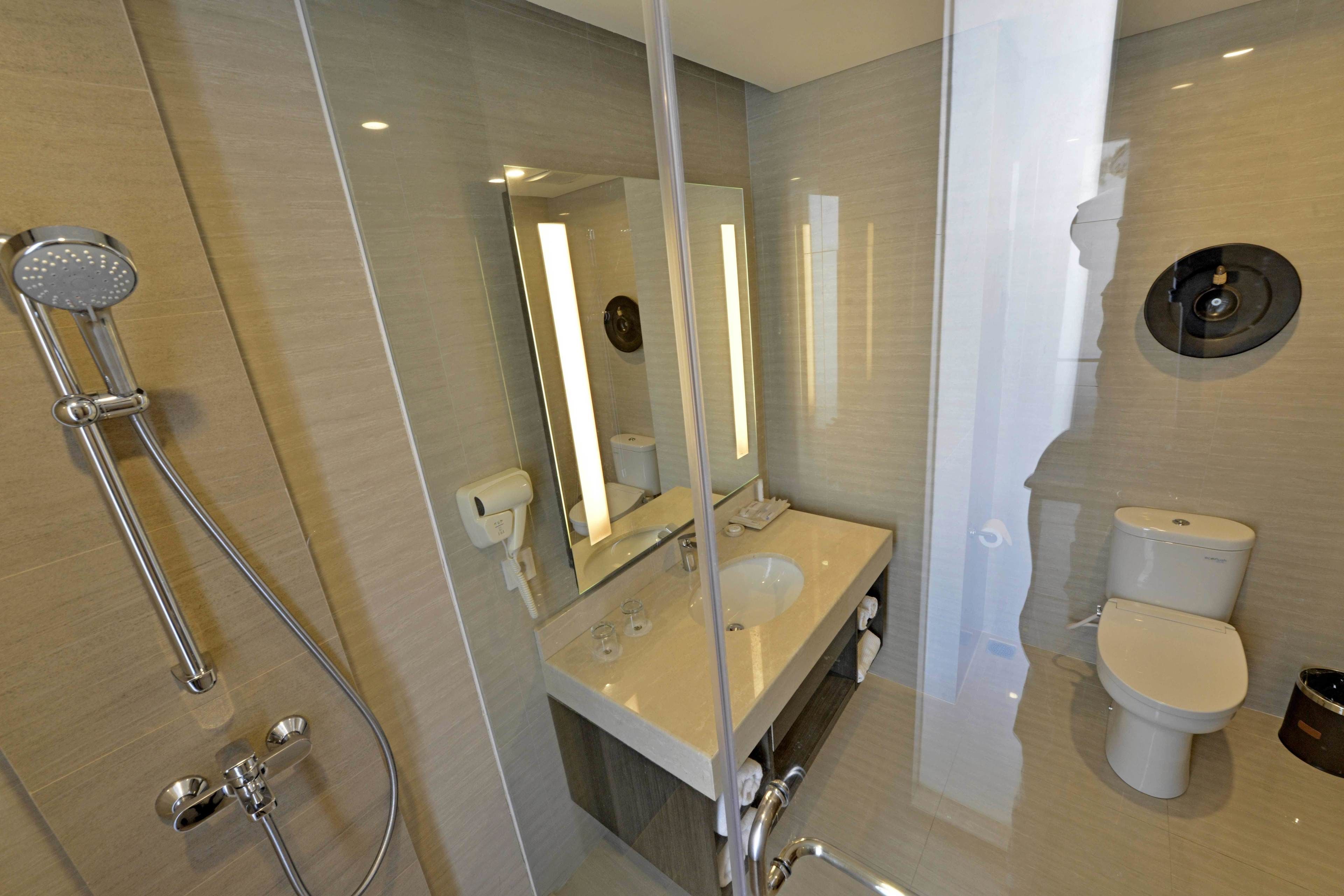 A modern bathroom with a glass-enclosed shower, a sink, a toilet, and a mirror.