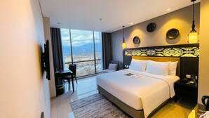 Une chambre d’hôtel avec un grand lit, un bureau, une chaise et une vue sur la ville.