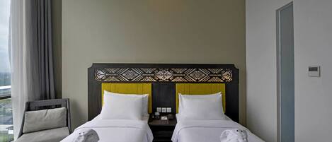 A hotel room with two beds, a chair, a nightstand, and a view of the outdoors.