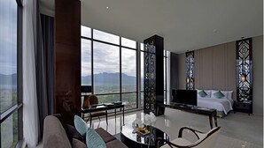 Une chambre d’hôtel moderne avec une grande fenêtre, un canapé, une table basse, une télévision et un lit.
