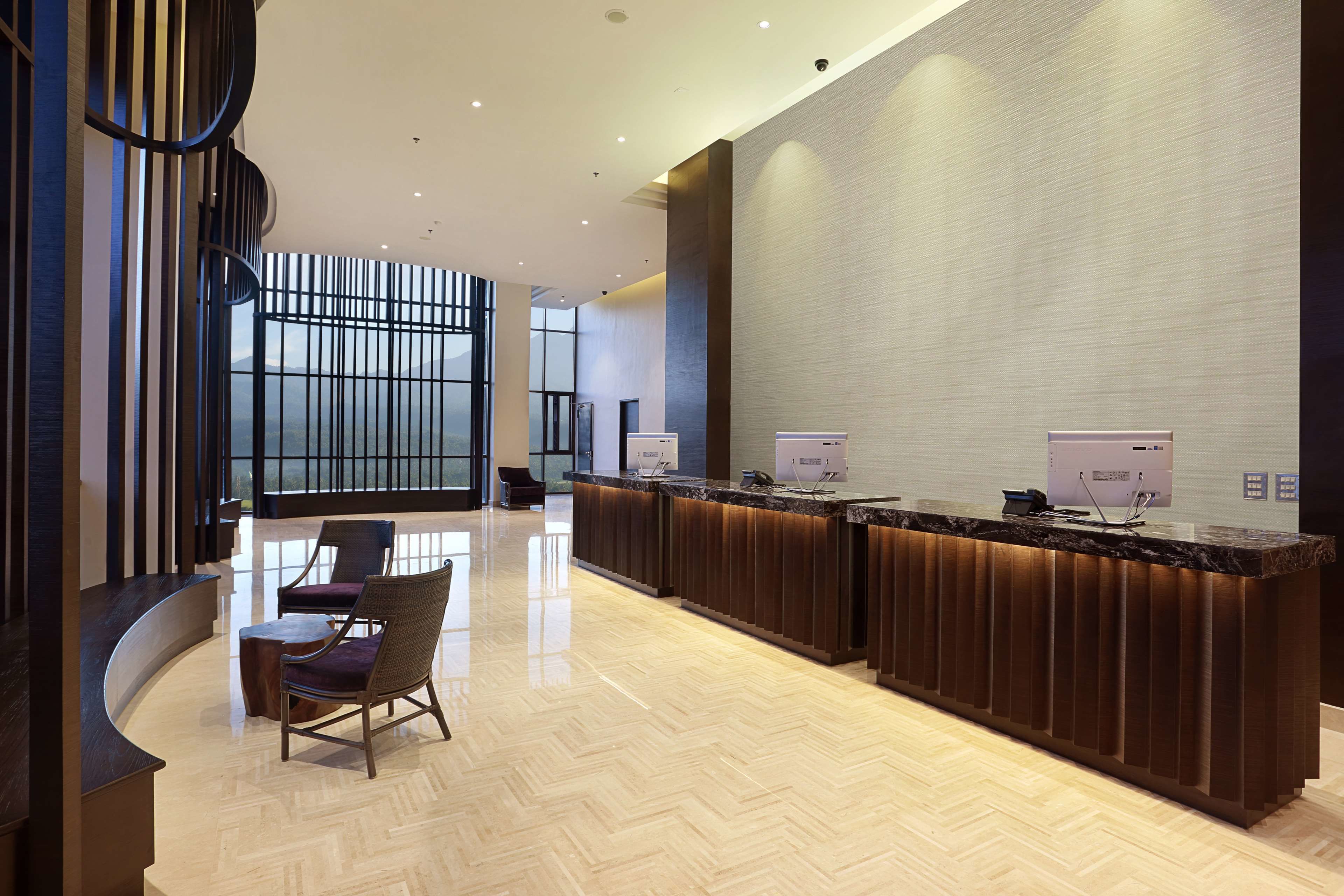 A modern reception area with a curved counter, two receptionists' stations, and a seating area with a chair and a small table.