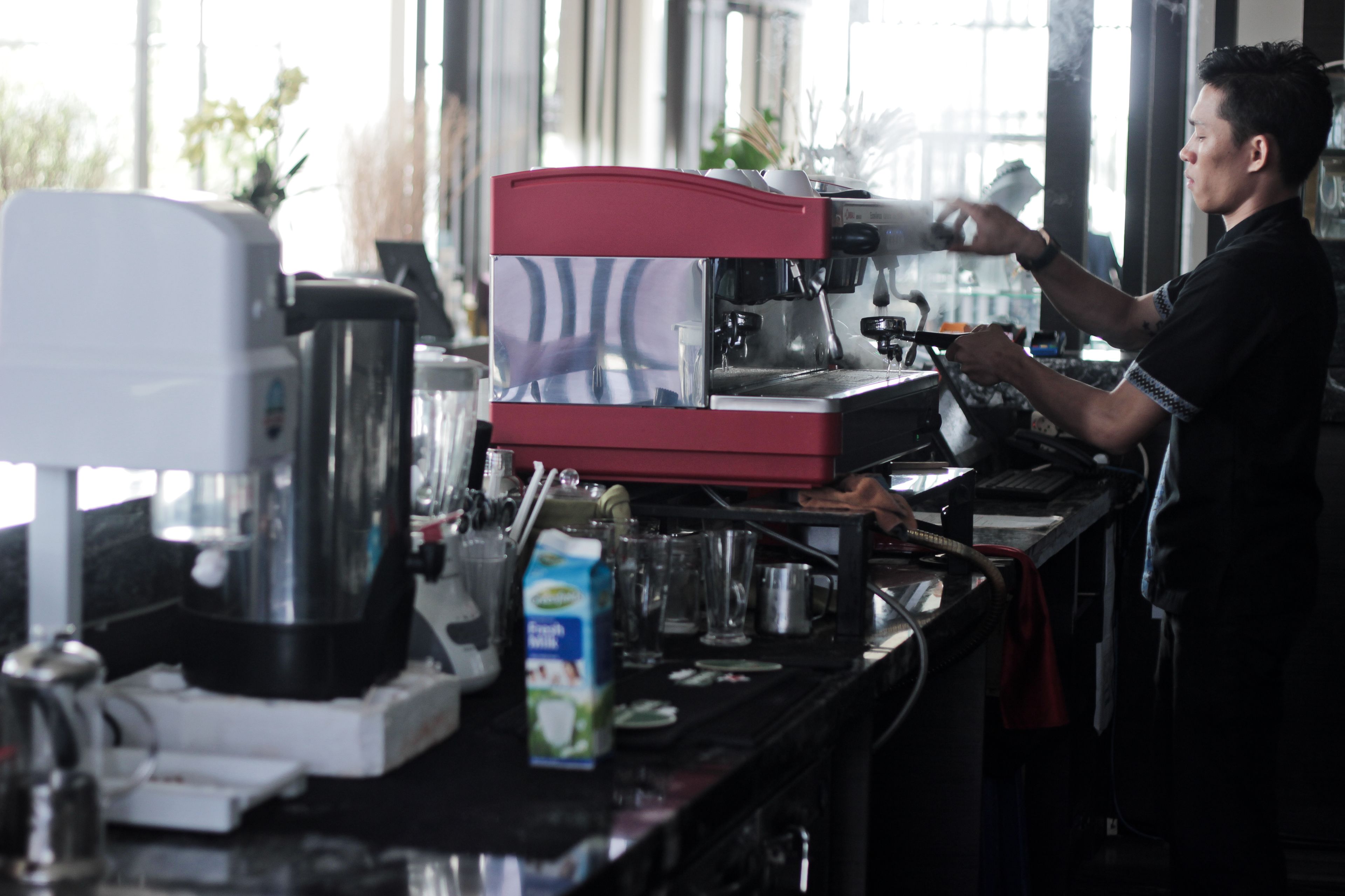 A barista preparing a drink at a coffee machine.