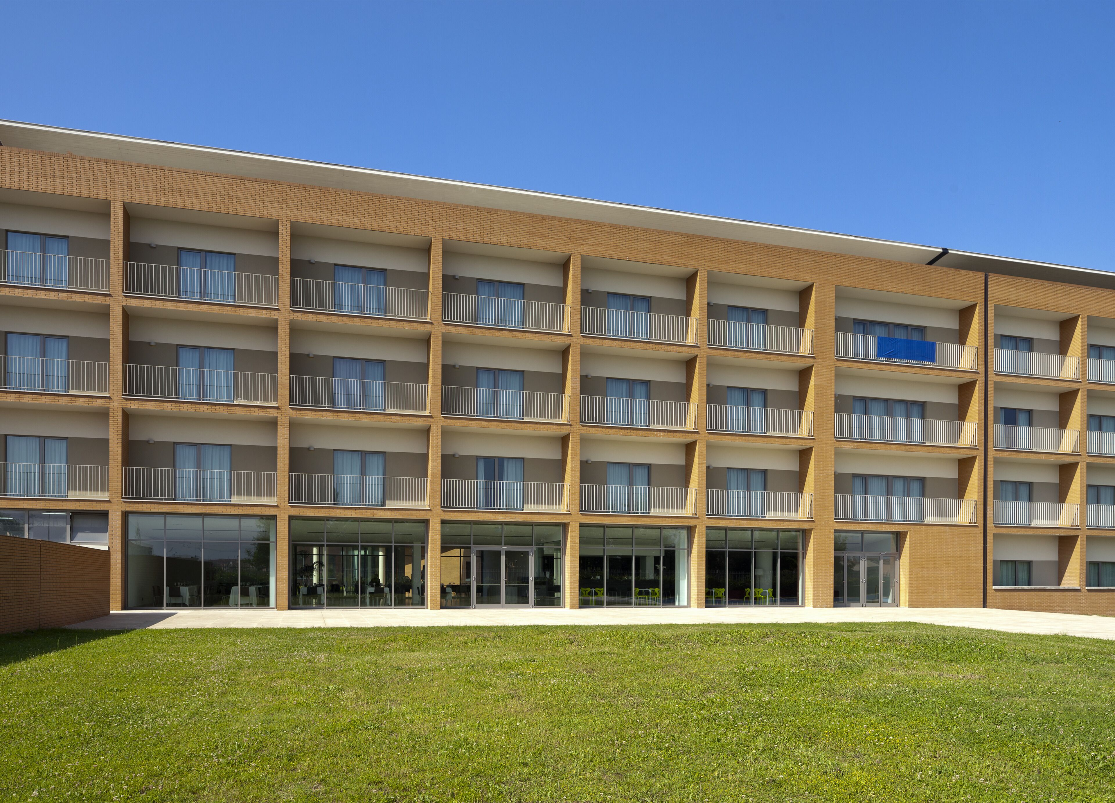 A multi-story building with a brick facade, large windows, and balconies.