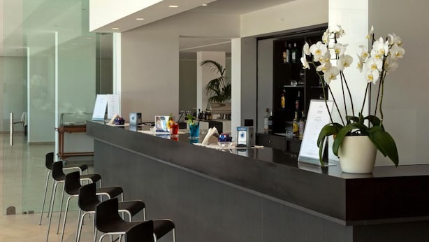Ein moderner Empfangsbereich mit einer langen Theke, schwarzen Stühlen und einer Orchideenpflanze im Topf.
