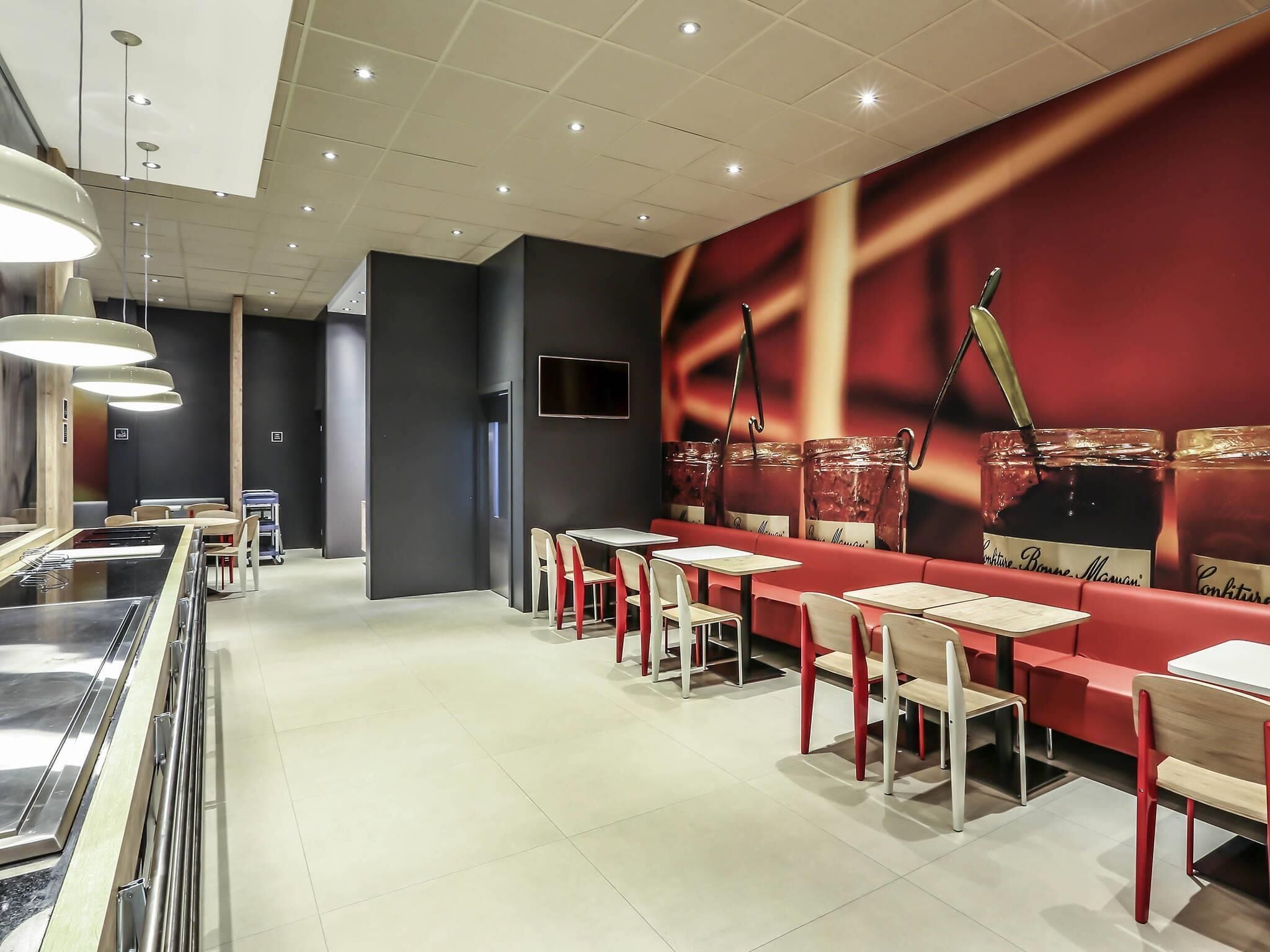 A modern restaurant interior with a long counter, multiple tables, and chairs.