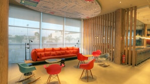 A modern interior with a red sofa, teal and red chairs, and a wooden partition. - ibis Sinop (Sinop)