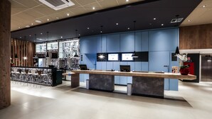 A modern reception area with a long reception desk, multiple monitors, and a wooden accent wall. - ibis Sinop (Sinop)