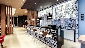 A modern bar area with a black and white mural, wooden accents, and contemporary bar stools. - ibis Sinop (Sinop)