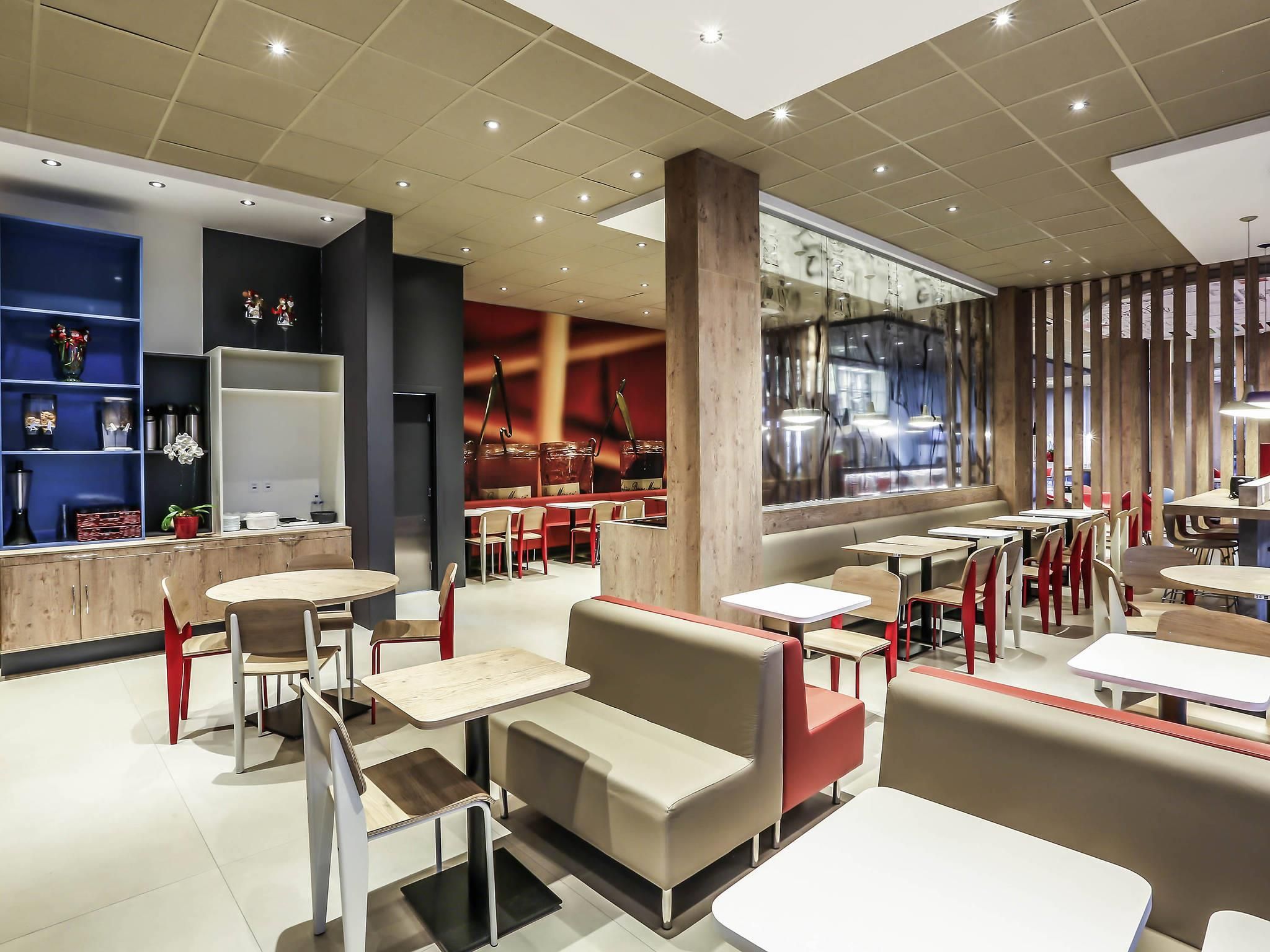 Un interior de restaurante moderno con cabinas, mesas y una zona de bar.
