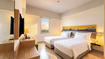 A hotel room with two beds, a desk, a mirror, and a window with a view.