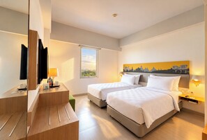 A hotel room with two beds, a desk, a mirror, and a window with a view. - Khas Malioboro (Yogyakarta)