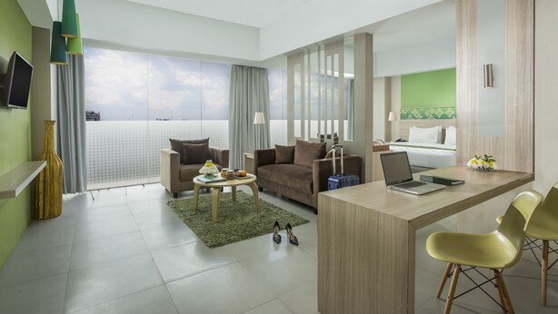 A modern hotel room with a large window, a desk with a laptop, a sofa, and a bed. -  KHAS Pekanbaru Hotel (Pekanbaru)