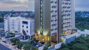 A modern hotel with a prominent 'KHAS' sign, featuring a central atrium with balconies, surrounded by lush greenery and a parking area. -  KHAS Pekanbaru Hotel (Pekanbaru)