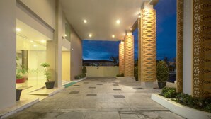 A hotel entrance with a tiled pathway, potted plants, and decorative columns. -  KHAS Pekanbaru Hotel (Pekanbaru)