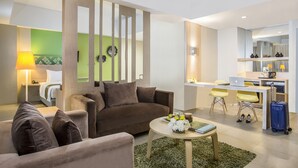 A modern living room with a sofa, a coffee table, and a dining area with a laptop and chairs. -  KHAS Pekanbaru Hotel (Pekanbaru)
