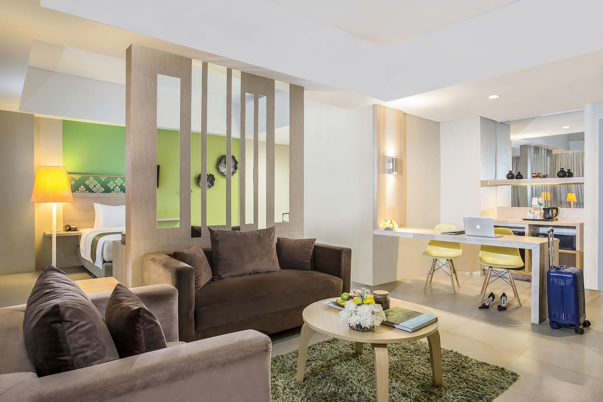 A modern living room with a sofa, a coffee table, and a dining area with a laptop and chairs.