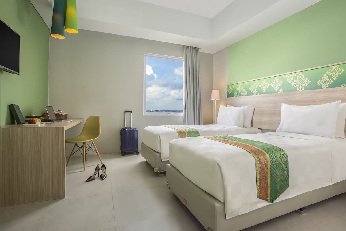 A hotel room with a large bed, a desk, a chair, and a suitcase.