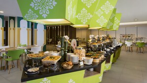 A buffet area with various food items and a green decorative wall. -  KHAS Pekanbaru Hotel (Pekanbaru)