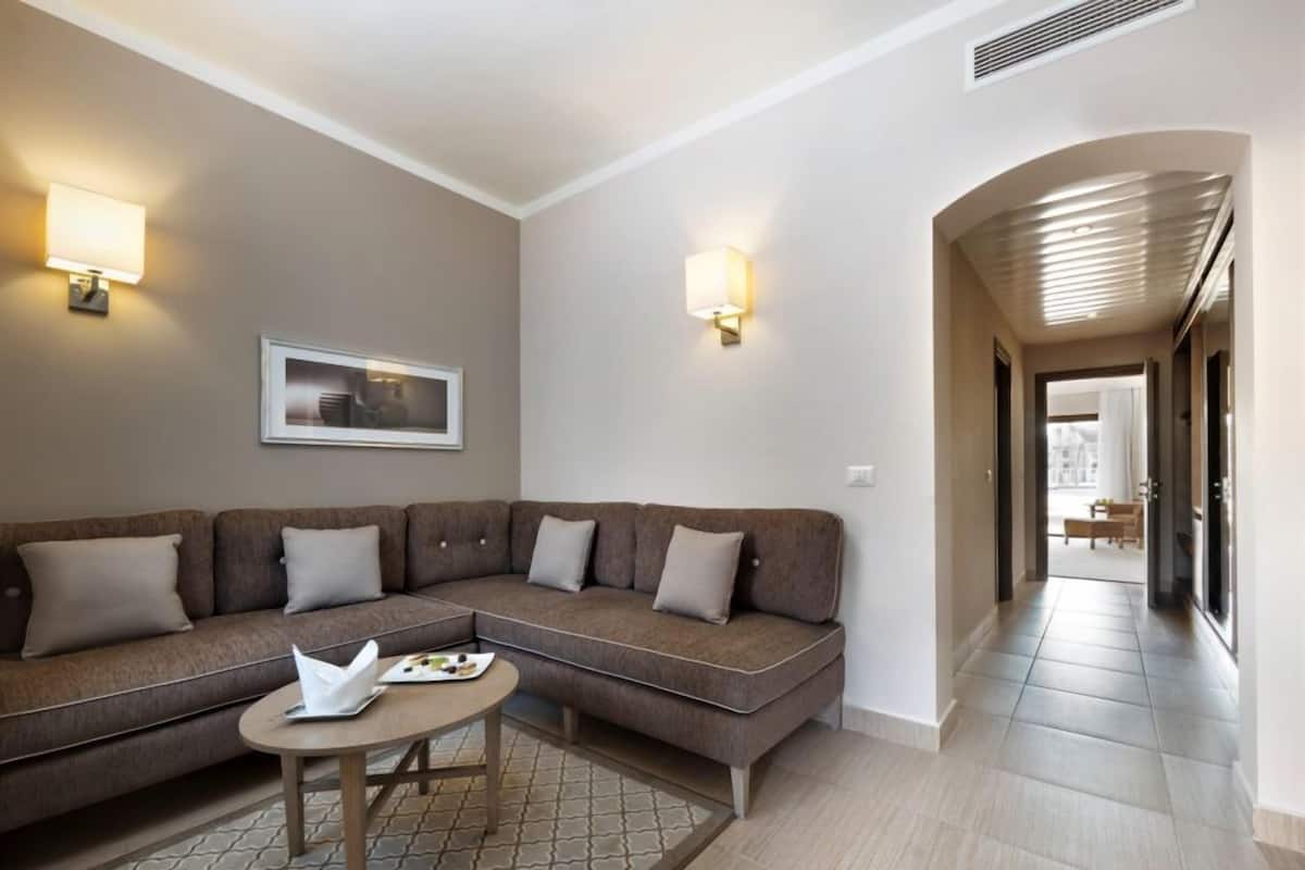A modern living room with a sectional sofa, a small round table, and two wall-mounted lamps.