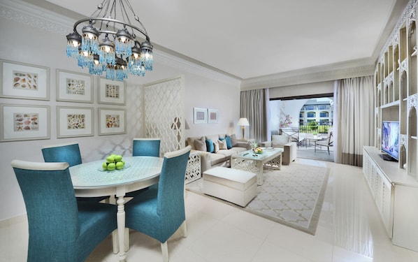 A spacious living room with a chandelier, dining area with teal chairs, and a balcony with a view. - Steigenberger Alcazar (Sharm El Sheikh)