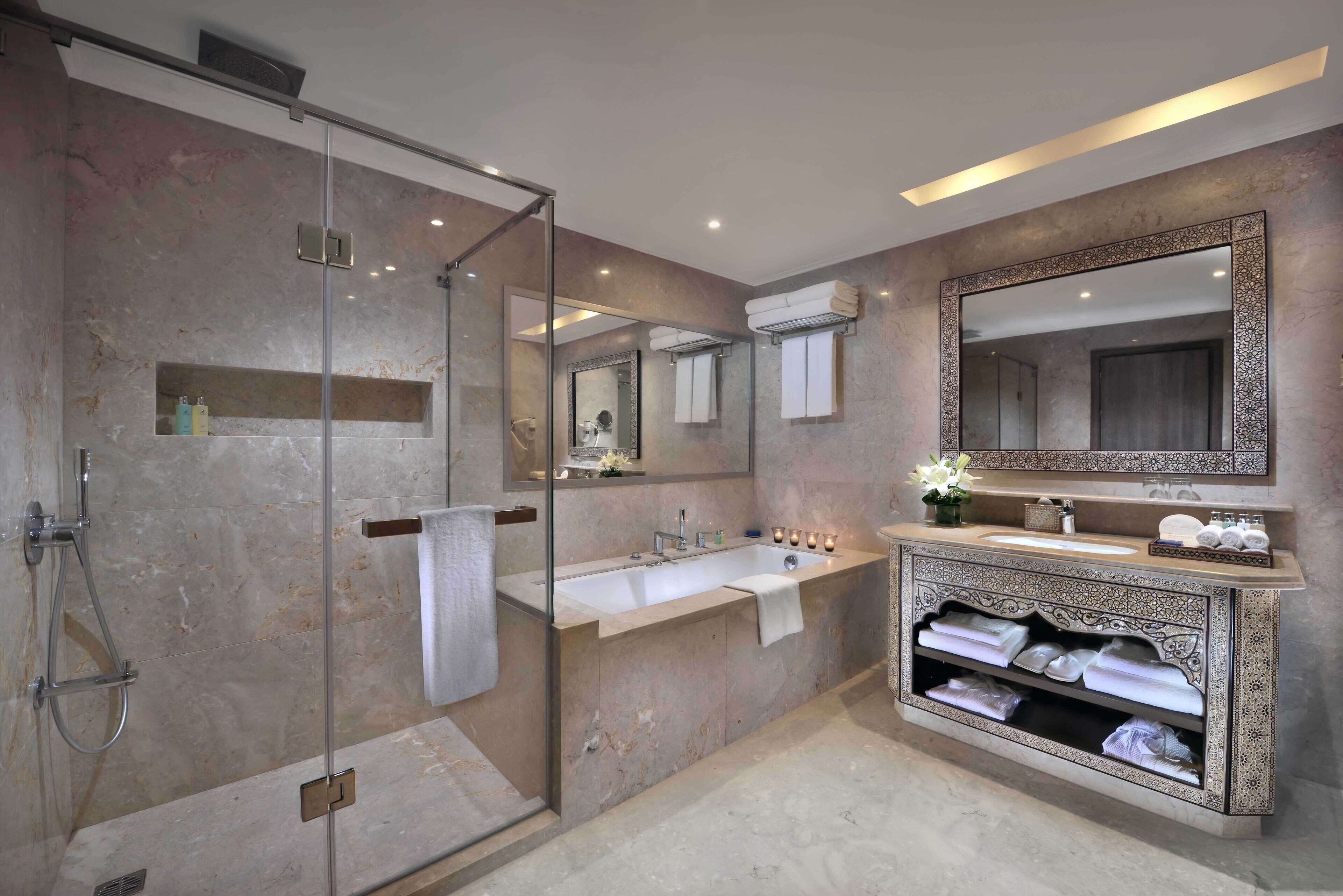 A modern bathroom with a glass-enclosed shower, a large mirror, and a vanity with a sink and towel rack.