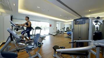 A gym with cardio machines, weight training equipment, and a mirrored wall.